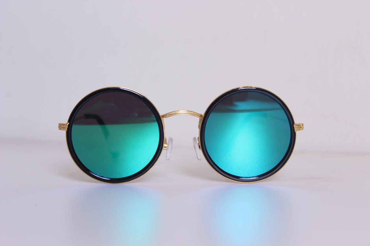 our-services-2 Elegant round sunglasses with blue-tinted lenses and gold frames, perfect for a trendy fashion statement.